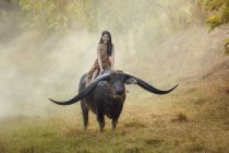 Mulher montando búfalo longhorn na natureza, Tailândia — Fotografia de Stock