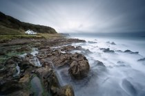 Ирландия, Ballycastle, живописный вид на дом на море и массивные скалы — стоковое фото