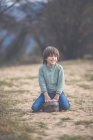 Smiling boy sitting on a rock on path — Stock Photo
