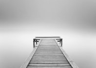 Empty wooden jetty in the mist, monochrome — Stock Photo