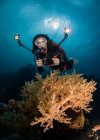 Hembra Scuba Diver fotografiando coral bajo el agua - foto de stock