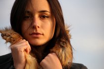 Junge Frau in warmem Mantel mit Pelzhaube blickt in die Kamera — Stockfoto