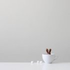 Coniglietto di cioccolato in una tazza bianca contro parete grigia — Foto stock