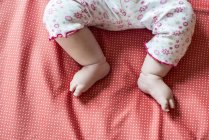 Image recadrée de bébé fille pieds sur le lit — Photo de stock