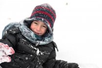 Sonriente chico acostado en la nieve al aire libre - foto de stock