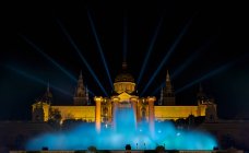 España, Cataluña, Barcelona, Vista nocturna de la Fuente Mágica contra la iluminada Plaza Espana - foto de stock