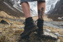 Close-up of tattoo on female leg and walking boots, rear view — Stock Photo