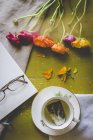 Чашка чаю вдень з книгою, окулярами та квітами на столі — стокове фото