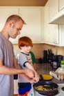 Батько і червоний волохатий син готують на кухні разом — стокове фото