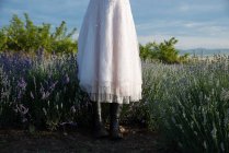 Femme portant une jupe et des bottes en caoutchouc debout dans un champ de lavande — Photo de stock