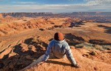 Соединенные Штаты Америки, Utah, Canyonlands National Park, Hiker sitting and looking at Buck Canyon — стоковое фото