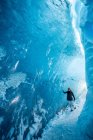 Mulher caminhando através de caverna de gelo glacial na Islândia — Fotografia de Stock