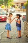 Two cute sisters sharing ice cream on city street — Stock Photo