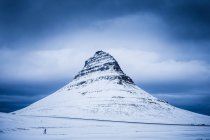 Vista panorámica del excursionista caminando por la montaña Kirkjufell en invierno, Grundarfjordur, Islandia - foto de stock
