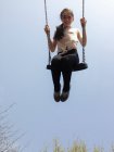 Portrait of smiling girl on swing in front of blue sky — Stock Photo