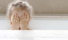 Retrato de uma menina sentada em um banho cobrindo o rosto com as mãos — Fotografia de Stock