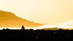 Силуэт серфера, отдыхающего на пляже на закате — стоковое фото
