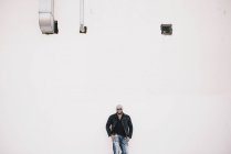 Холодный человек стоит перед белой стеной — стоковое фото