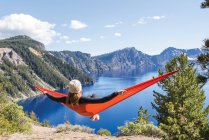Woman sitting in hammock in nature and looking at view, Crater Lake, Oregon, America, USA — Stock Photo