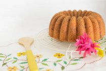 Bundt cake with flowers against white wall — Stock Photo