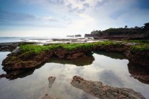 Rocce ricoperte di muschio sulla spiaggia di Mengening con bassa marea, Bali, Indonesia — Foto stock
