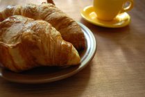 Croissants und Tasse Kaffee über Holztisch, Nahaufnahme — Stockfoto