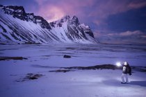 Frau steht in der Winterlandschaft mit Bergen und hält Fackel, hofn, hornafjordur, Island — Stockfoto
