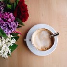 Overhead view of coffee and flowers on table — Stock Photo