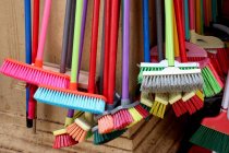 Close-up of multi-colored brooms hanging on wall in market — Stock Photo