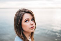 Porträt einer Frau mit braunen Haaren, die vor dem Meer steht — Stockfoto
