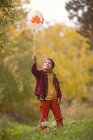 Menino segurando um balão na floresta de outono — Fotografia de Stock