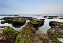 Vista panorâmica de Moss rochas cobertas ao pôr do sol, Mengening praia, Bali, Indonésia — Fotografia de Stock