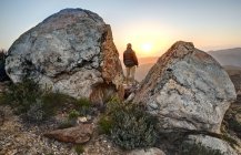 Hombre de pie en la cima de la montaña y mirando el atardecer, McCain Valley, California, Estados Unidos - foto de stock