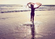 Женщина бежит по пляжу с американским флагом над головой — стоковое фото