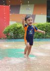 Хлопчик в купальнику грає у водному фонтані — стокове фото