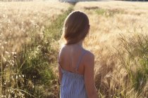 Visão traseira de uma menina de pé em um campo de trigo, itália — Fotografia de Stock