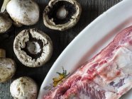Rohe Schweinerippchen und frische Pilze über dem Tisch — Stockfoto