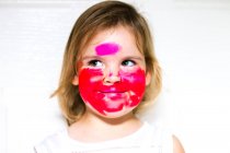 Retrato de uma menina com batom em todo o rosto olhando para o lado — Fotografia de Stock