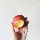 Close-up of a peach with a bite mark against white wall — Stock Photo