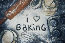 J'aime la cuisson écrite dans la farine sur une table — Photo de stock