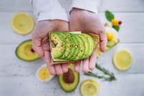 Close-up of human hands holding avocado sandwich — Stock Photo