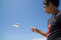 Портрет мальчика, летящего воздушным змеем перед голубым небом — стоковое фото