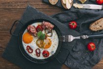 Fried eggs, bacon and cherry tomatoes with bread — Stock Photo