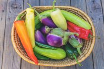 Basket with fresh peppers and, aubergines, chilies and zucchini — Stock Photo