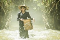 Jeune femme à la recherche de poissons dans le ruisseau, Thaïlande — Photo de stock