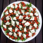 Salad with lentils, tomatoes and goats cheese in white plate, top view — Stock Photo