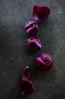Fresh red cabbage leaves in a row on dark surface — Stock Photo