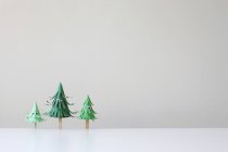 Trois arbres artisanaux en papier avec les yeux contre le mur blanc — Photo de stock