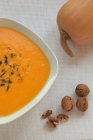 Bowl of pumpkin soup and nuts over table — Stock Photo