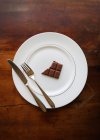 Bar of half eaten chocolate on a plate with a knife and fork — Stock Photo
